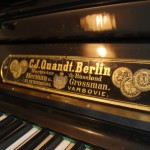 widok na nazwę pianina Pianino Herman & Grossman umieszczoną na pokrywie klawiatury widok z boku